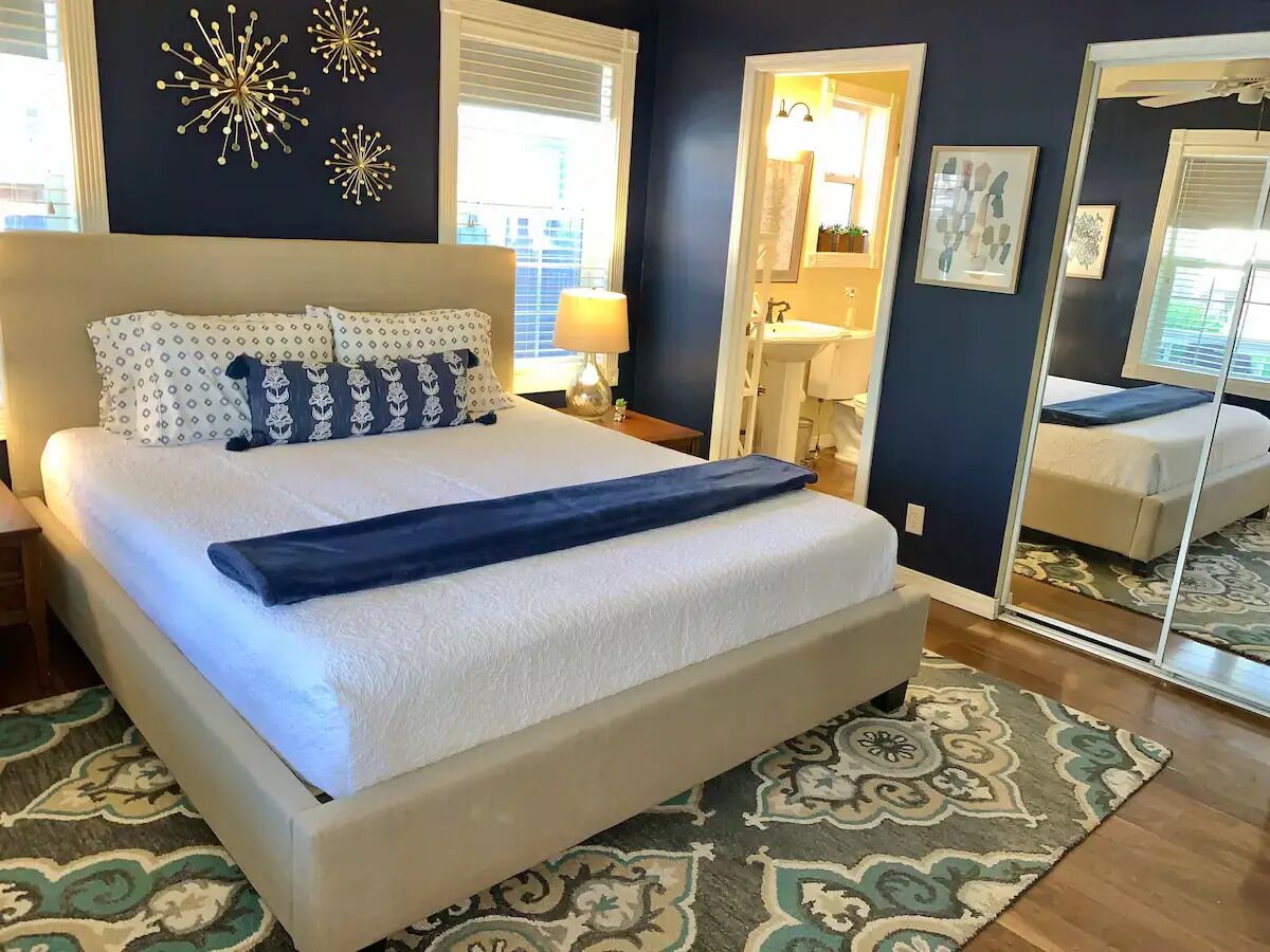 Un dormitorio con una cama grande, una mesita de noche, un espejo y decoración mural.