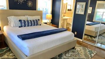 Un dormitorio con una cama grande, una mesita de noche, un espejo y decoración mural.