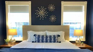 A neatly made bed with a blue bedspread, two matching lamps on nightstands, and decorative wall art. - Mountain Escape - Pet-Friendly - Fenced Yard - Fast WiFi - Near Flagstaff (Flagstaff)