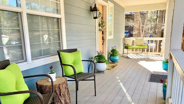 A covered porch with two wicker chairs, a small round table, and potted plants. - Mountain Escape - Pet-Friendly - Fenced Yard - Fast WiFi - Near Flagstaff (Flagstaff)