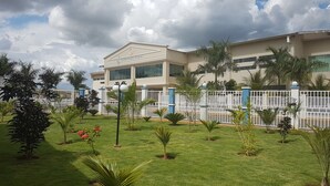 A building with a beige facade, surrounded by a white fence and palm trees. - Lacqua diroma (Caldas Novas)
