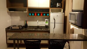 A compact kitchen with a granite countertop, a built-in microwave, a refrigerator, and a coffee maker. - Lacqua diroma (Caldas Novas)