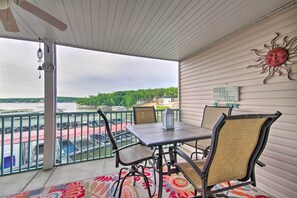 A balcony with a table and chairs, overlooking a river with boats and greenery. - Furnished Balcony, Pool! Waterfront Lake Ozark Gem (Lake Ozark)