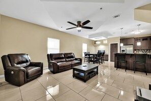 A spacious living room with a brown leather sofa, a recliner, and a coffee table.