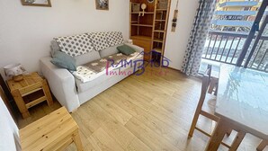 Un salón acogedor con sofá, una mesita de madera y una zona de comedor con mesa y sillas.