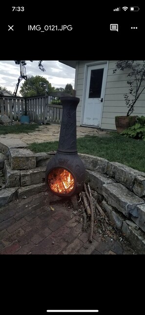 Guests can enjoy a warm ambiance by the backyard stove, surrounded by a brick-paved area and a stone wall.