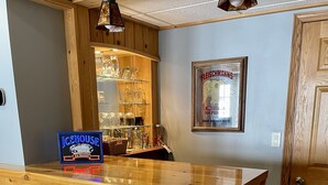 Zona de bar con mostrador de madera, pared de piedra y un letrero que dice 'Icehouse Ice Brewed'.