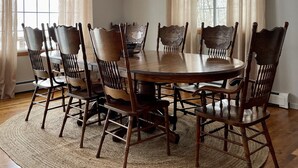 Comedor con una mesa redonda, sillas de madera, alfombra tejida y un diseño de techo único.