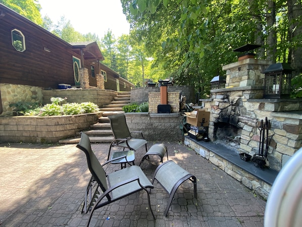 Une terrasse extérieure avec des marches en pierre menant à un bâtiment en bois, le tout entouré de verdure.