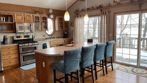 Una cocina moderna con armarios de madera, electrodomésticos de acero inoxidable y una isla grande con taburetes de bar.