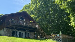 Un lodge rústico con fachada de piedra, balcón de madera y una escalera que lleva a una terraza superior.