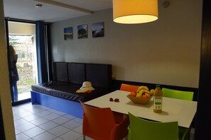 A dining area with a table, chairs, a bowl of fruit, and a bottle of juice.