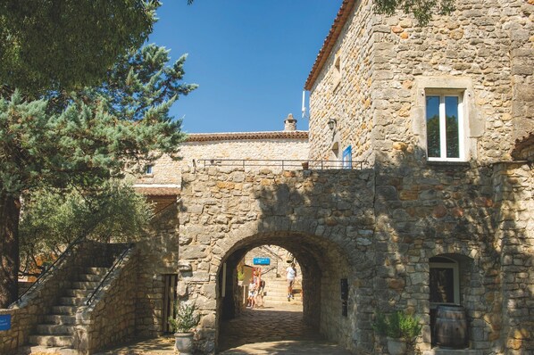 A stone building with an archway entrance, a staircase, and a small window.