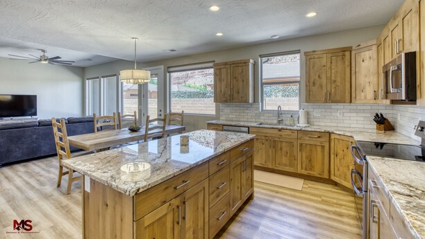A modern kitchen with wooden cabinets, granite countertops, and a central island. - Modern Luxury Home in Kanab, Utah with Hot Tub & Pool! Near Zion National Park, Bryce Canyon, the Grand Canyon, and the Coral Pink Sand Dunes! (Kanab)