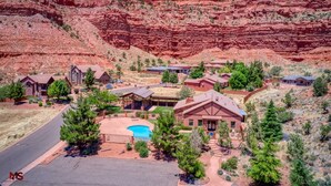 A residential area with houses, a swimming pool, and a mountainous backdrop. - Modern Luxury Home in Kanab, Utah with Hot Tub & Pool! Near Zion National Park, Bryce Canyon, the Grand Canyon, and the Coral Pink Sand Dunes! (Kanab)