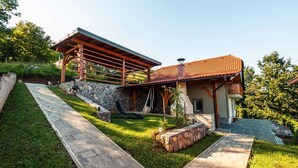 A modern house with a stone foundation, a wooden pergola, and a red-tiled roof. - Holiday house rustically furnished (Dvor)
