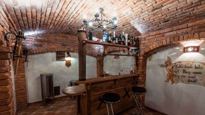 A rustic bar area with a brick ceiling, wooden bar counter, and stools. - Holiday house rustically furnished (Dvor)