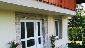 A two-story house with a balcony, a stone facade, and a paved patio. - Holiday house rustically furnished (Dvor)