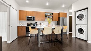Une cuisine moderne avec des meubles en bois, des appareils électroménagers en acier inoxydable et un îlot central doté de tabourets de bar.