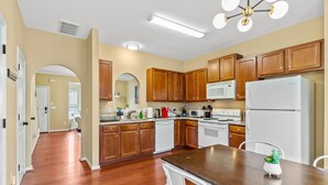 A modern kitchen with wooden cabinets, a central island, and white appliances.