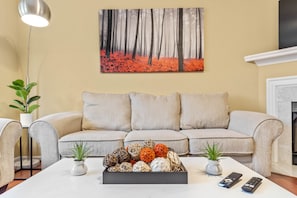 A living room with a sofa, a coffee table with decorative items, and a painting on the wall.