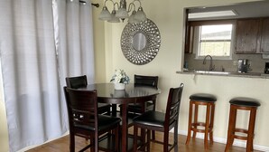 Een eetgedeelte met een ronde tafel, vier stoelen en twee barkrukken.