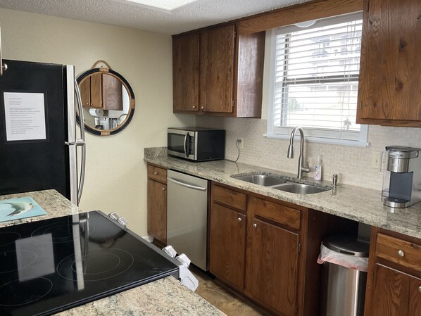 A compact kitchen with wooden cabinets, a microwave, a dishwasher, a sink, and a coffee maker. - New, Amazing Panoramic views of Lake Hamilton, waterfront at The Landing. (Hot Springs)
