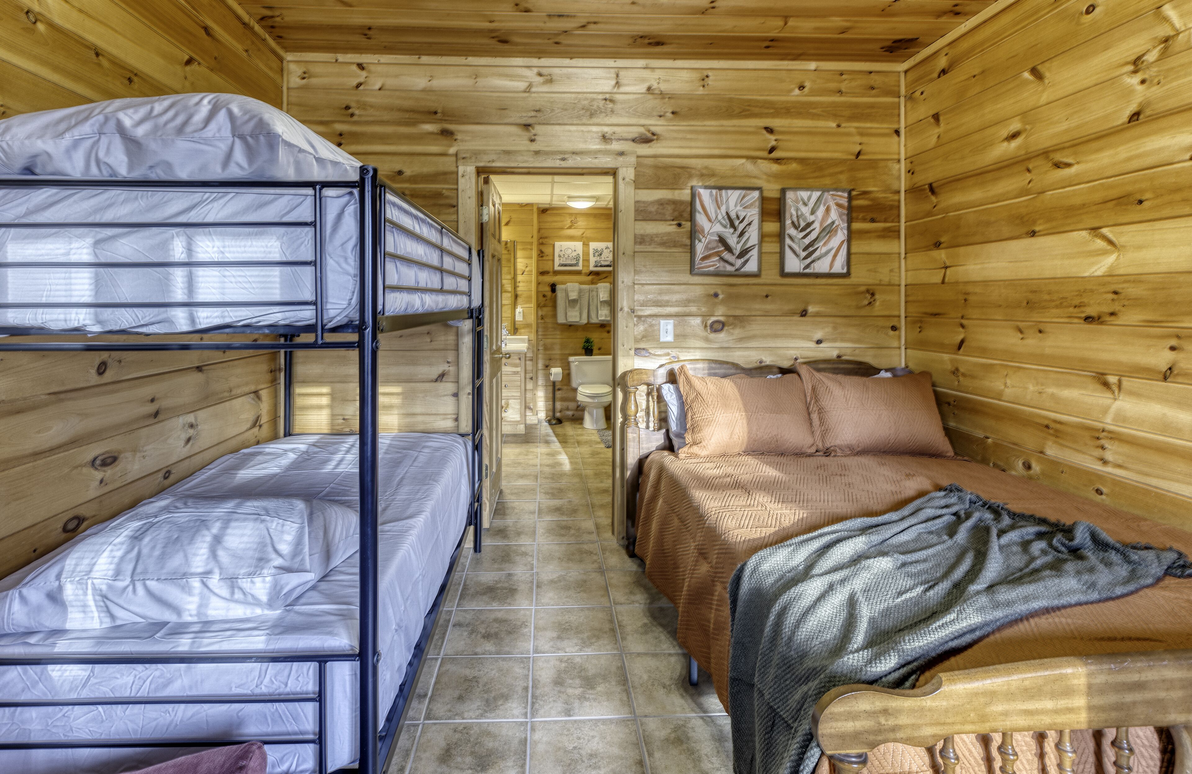 A cabin with bunk beds, a single bed, and a bathroom visible through an open door.