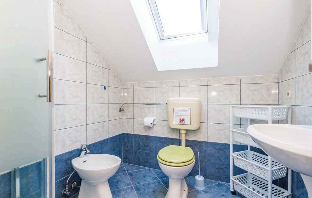 A bathroom with a skylight, a toilet, a bidet, and a sink.