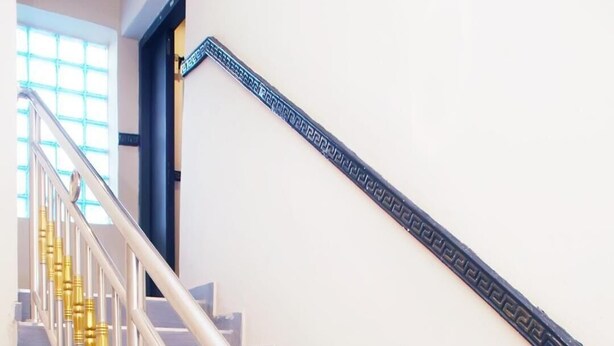 A staircase with metallic handrails and golden balusters.