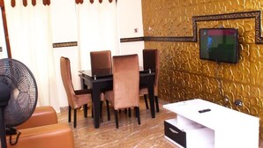 A room with a dining area, a TV mounted on a textured wall, and a white entertainment unit.