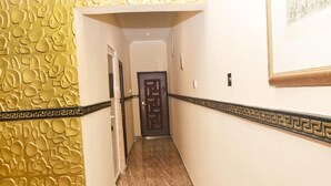 A hallway with a patterned wall, a marble floor, and a decorative door.