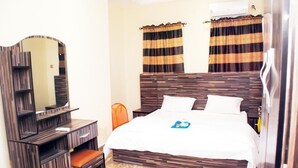 A hotel room with a bed, a dresser, a mirror, and curtains.