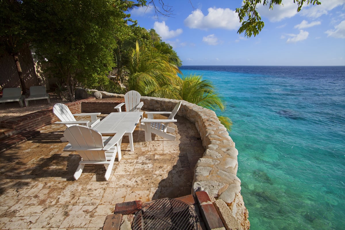 An outdoor seating area with a stone wall and a view of the ocean.