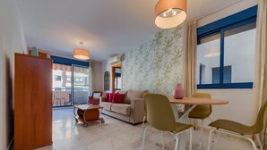 Una sala de estar moderna con sofá, sillas, una mesa de comedor y vistas al exterior.