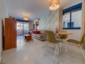 Una sala de estar moderna con sofá, sillas, una mesa de comedor y vistas al exterior.