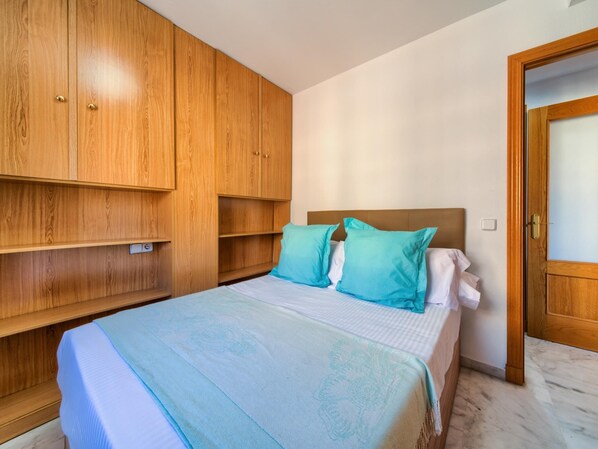 Un dormitorio con cama, dos almohadas, un armario de madera y una puerta.