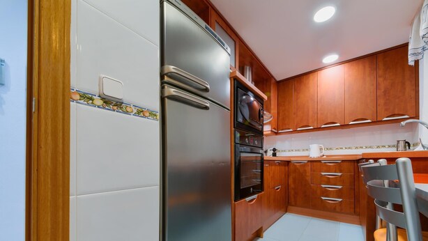 Una cocina compacta con refrigerador, horno y armarios de madera.