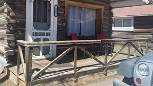 A rustic log cabin with a wooden porch, a door with a number plate, and a car parked in front. - THE FRAN - WALK EVERYWHERE IN DOWNTOWN CREEDE! 1 bedroom, 1 bath (SLEEPS 2) (Creede)