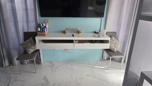 A room with a TV mounted on a wall, a white console table with drawers, two chairs with patterned cushions, and a marble floor. - The view!!!  (White bay jost van dyke)
