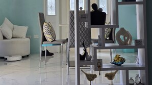 A modern living room with a white sofa, a clear glass coffee table, and a decorative wall piece. - The view!!!  (White bay jost van dyke)
