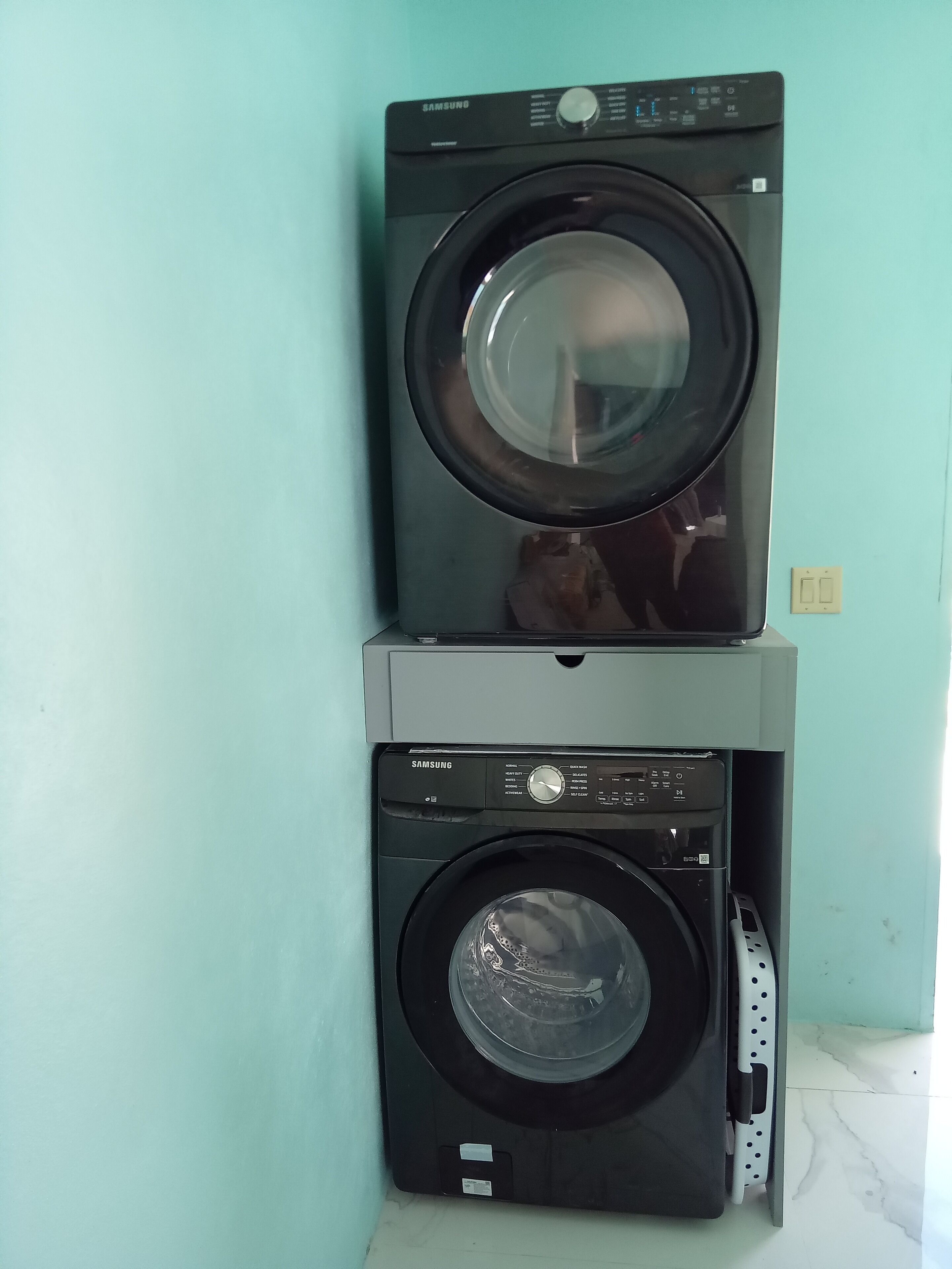 Two stacked washing machines against a light blue wall.
