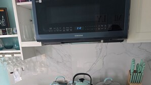 A kitchen with a black Samsung oven, a microwave above it, and a TV on the wall. - The view!!!  (White bay jost van dyke)