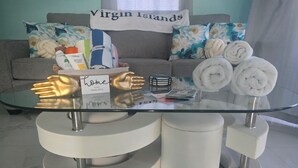 A glass-top table with white cylindrical stools, a sign reading "home is our happy place", and a couch with floral pillows in the background. - The view!!!  (White bay jost van dyke)