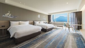 Ein Hotelzimmer mit zwei Betten, einem Sofa, einem Tisch und Blick auf Berge.