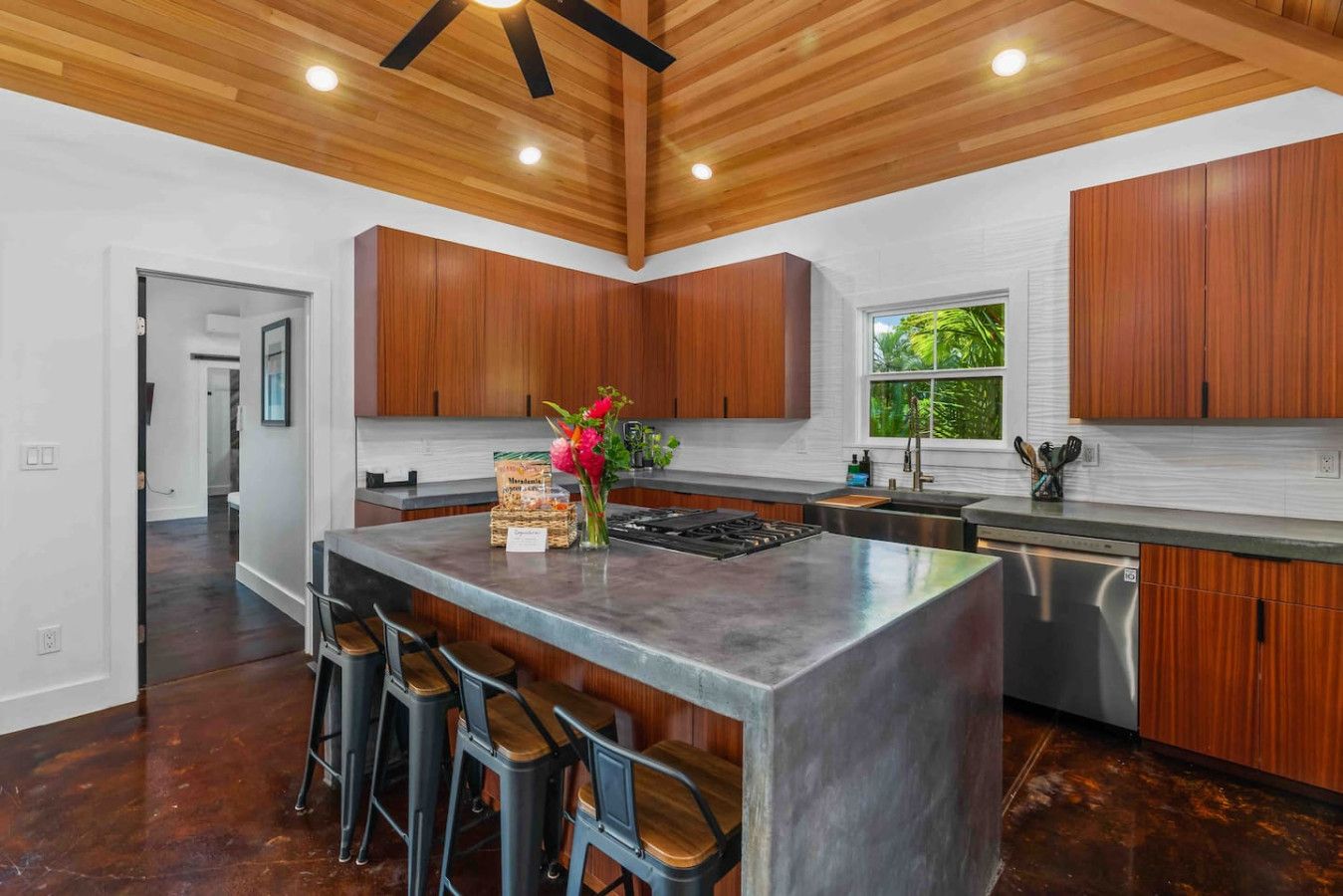 Una cucina moderna con mobili in legno, un'isola centrale con sgabelli, una finestra con vista e una ventola a soffitto.