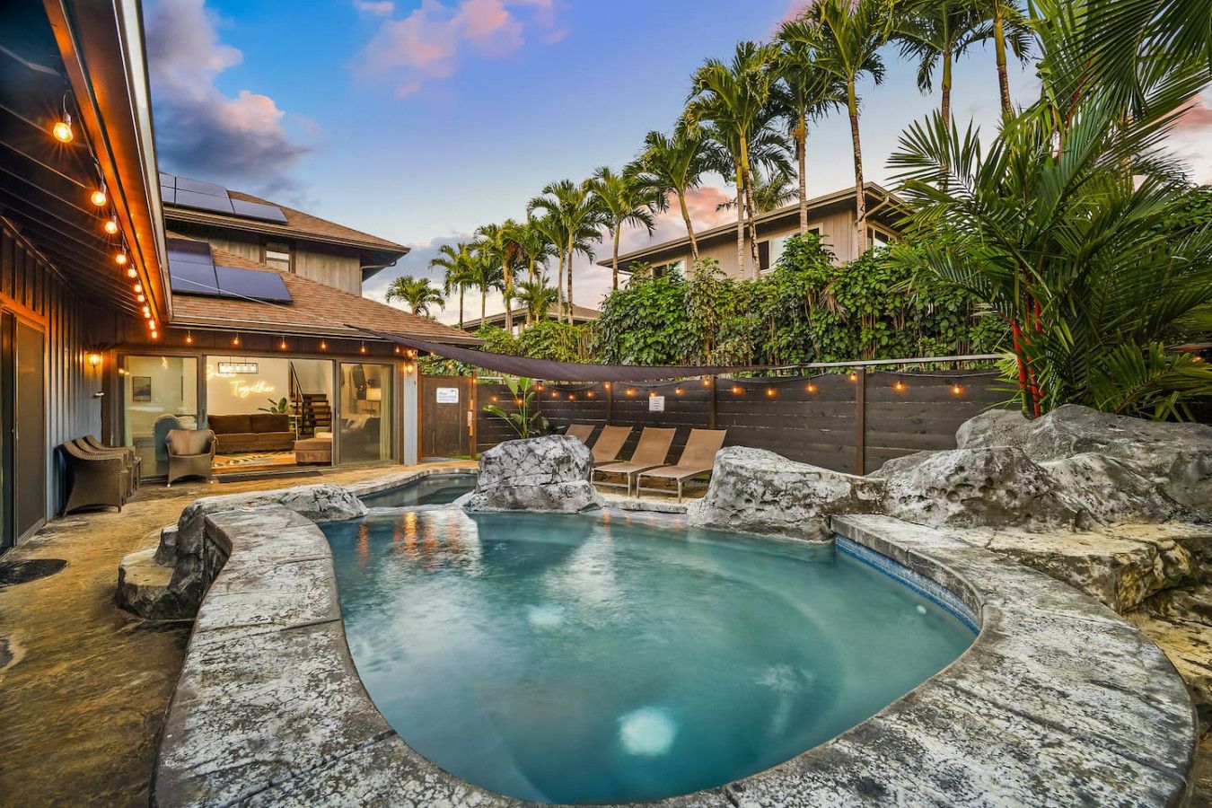 Un jardin avec un jacuzzi, des chaises longues et une piscine.