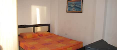 Ein Schlafzimmer mit einem Bett, einem Bild an der Wand und einem Heizkörper auf dem Boden.