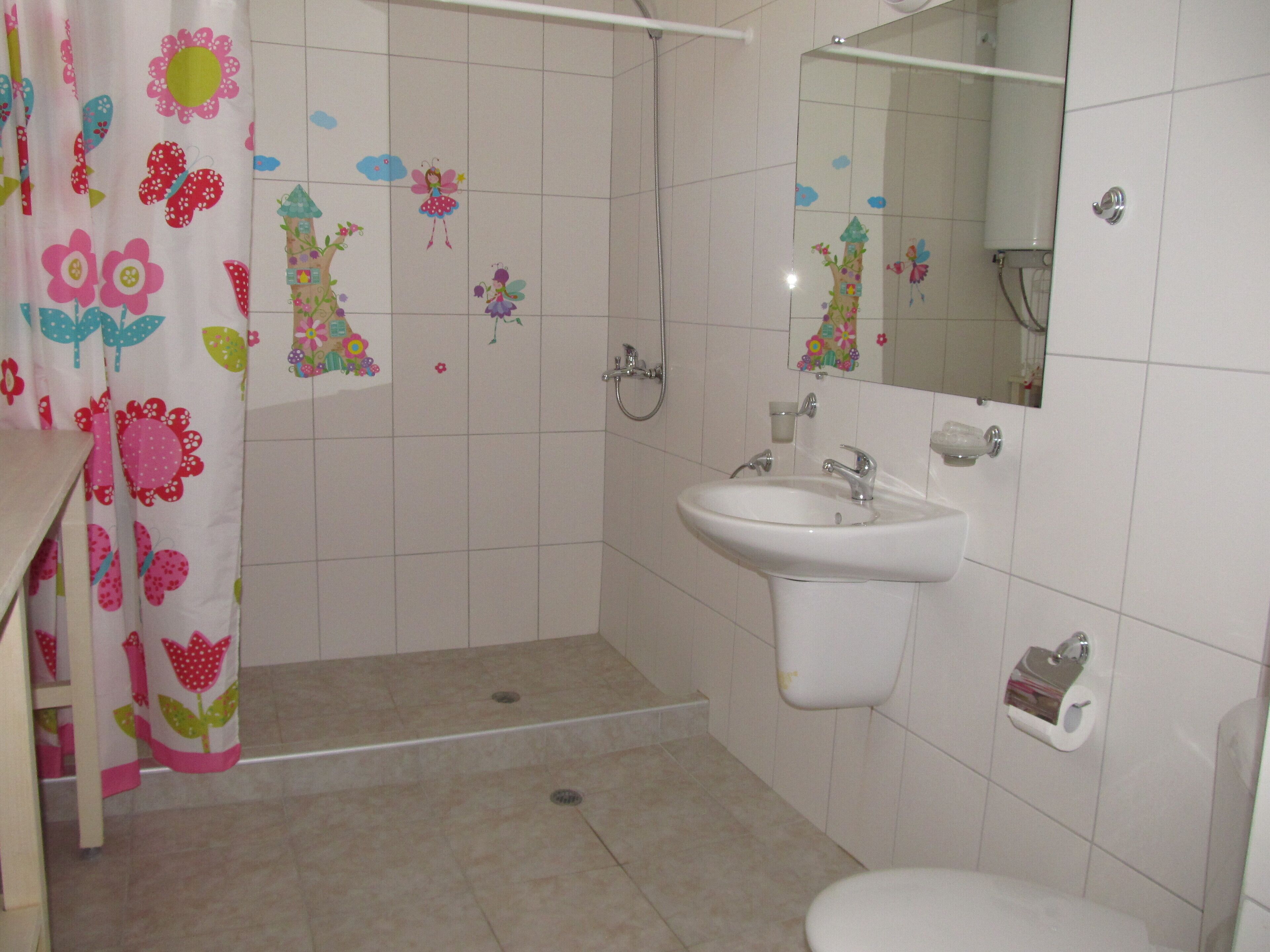 A bathroom with a shower, sink, toilet, and a mirror.