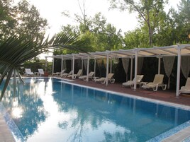 Una piscina con sillones de descanso y una zona cubierta.
